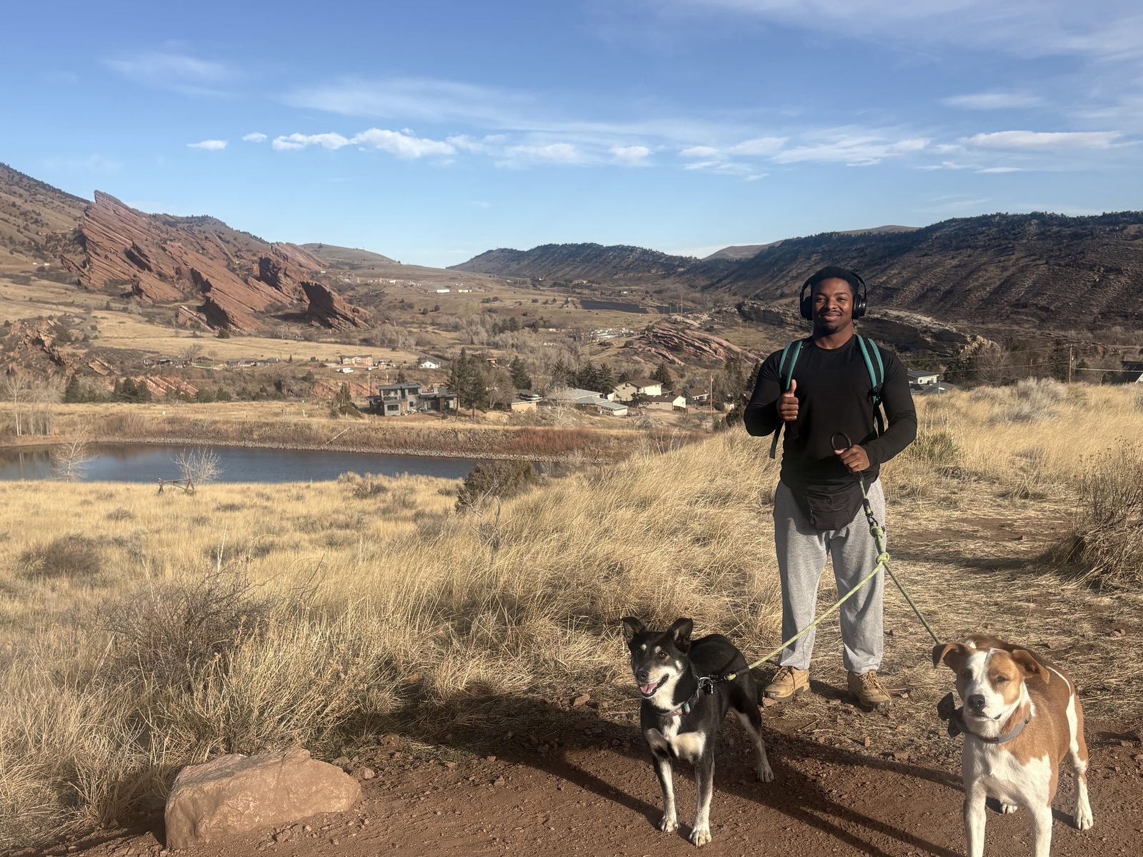 JD hiking with two client dogs above a reservoir near Red Rocks
