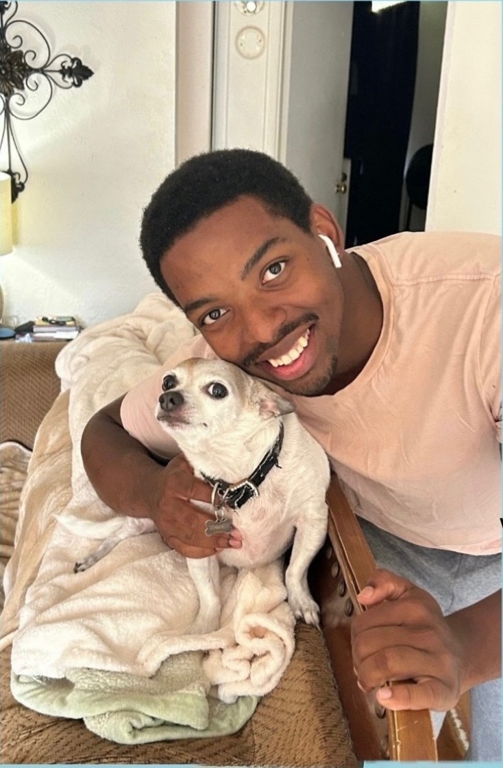 Paw & Order owner JD smiling with a happy client dog wrapped in a blanket
